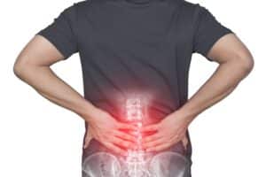 Man holding his lower back in discomfort, illustrating symptoms of sacroiliac pain and chronic bone pain affecting mobility and posture.