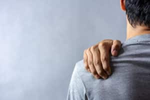 Middle-aged man holding shoulder in pain, illustrating cancer-related shoulder pain