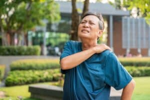 Elderly man in sportswear suffering from neck and shoulder pain due to poor posture and muscle inflammation
