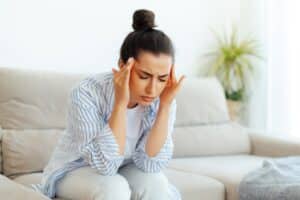 Woman at home with hands on her head due to headache in Oceanside, CA