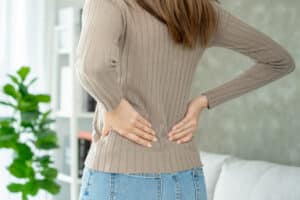 Woman holding her lower back due to herniated disc pain.